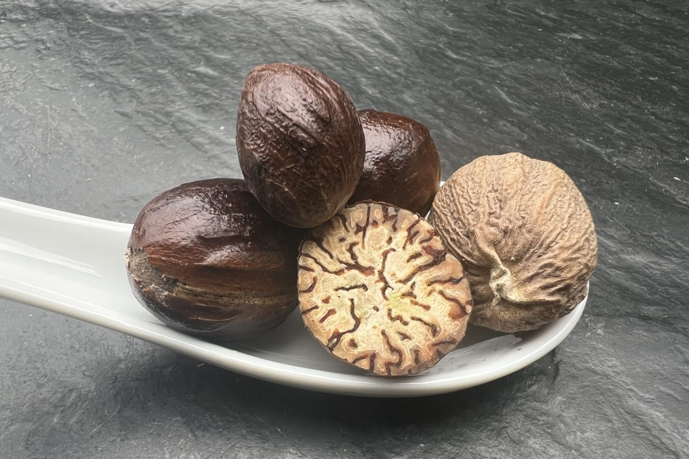 Muskatnuss Ein Löffel mit einem Haufen Muskatnüsse.