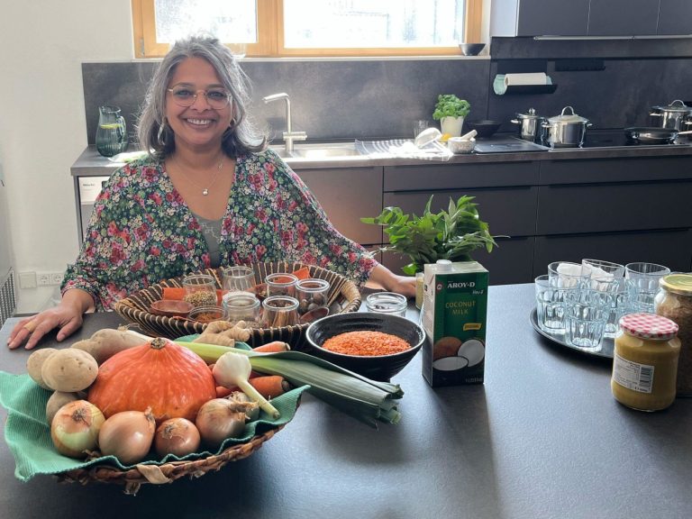Kochkurs Selvi in einer Küche mit Gewürzen, Gemüse und weiteren Zutaten vor sich, um ein leckeres Essen zu zaubern.